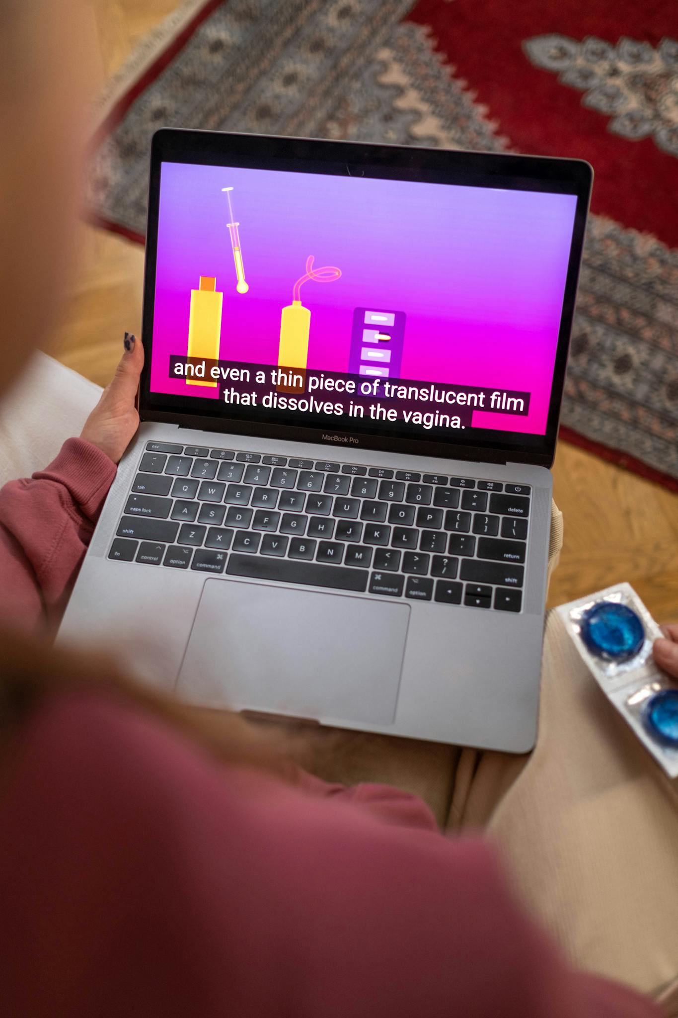 Person holding laptop with sex education video and condoms.
